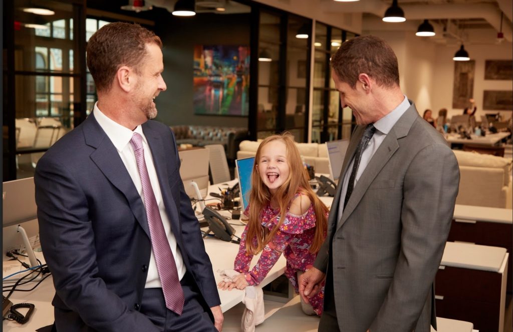 Alex and Orlando with a young kid playing in the office